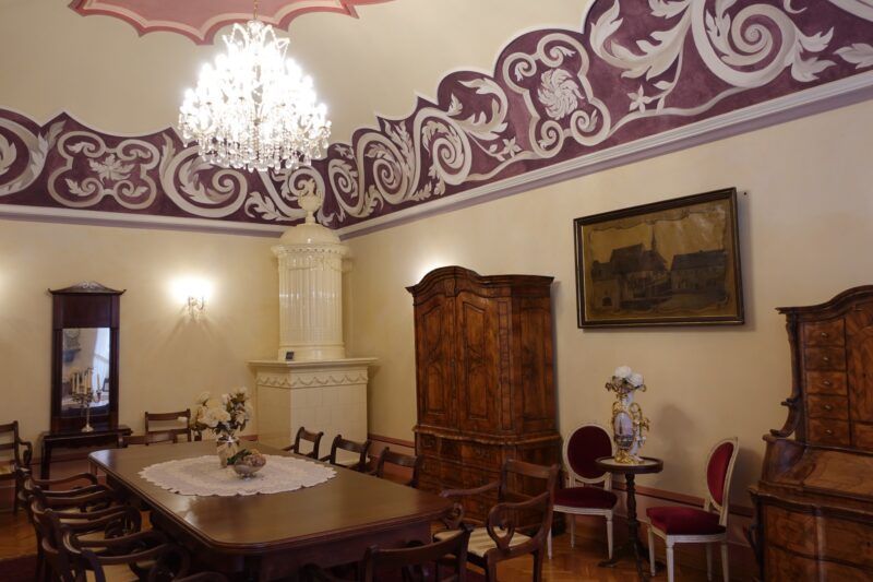 oświetlone wnętrze pokoju w muzeum ze zdobionym sufitem obrazem na ścianie i szafą 