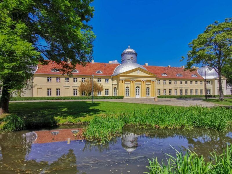 Pałac w kolorze żółtym z czerwonym dachem i kopułowym sklepieniem w centralnej części