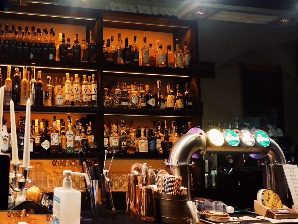 Bar w restauracji, widoczny regał, na którym są wystawione napoje alkoholowe.