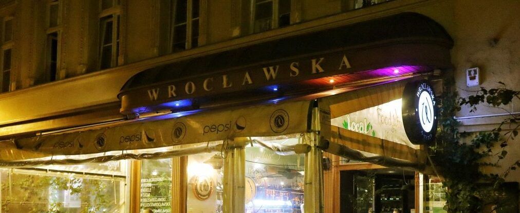 Wejście do restauracji, przed restauracją taras ze stołami i siedzeniami.