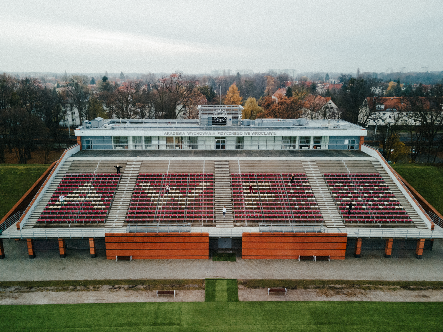 Widok na truby przy stadionie na terenie akademii wychowania fizycznego, krzesła trybun są czerwone a niektóre z nich białe, tworzą napis AWF