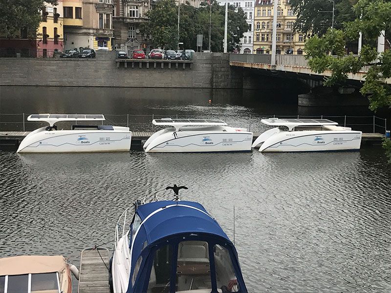 Widok na poustawiane na wodzie trzy katamarany w kolorze białym jeden obok drugiego.