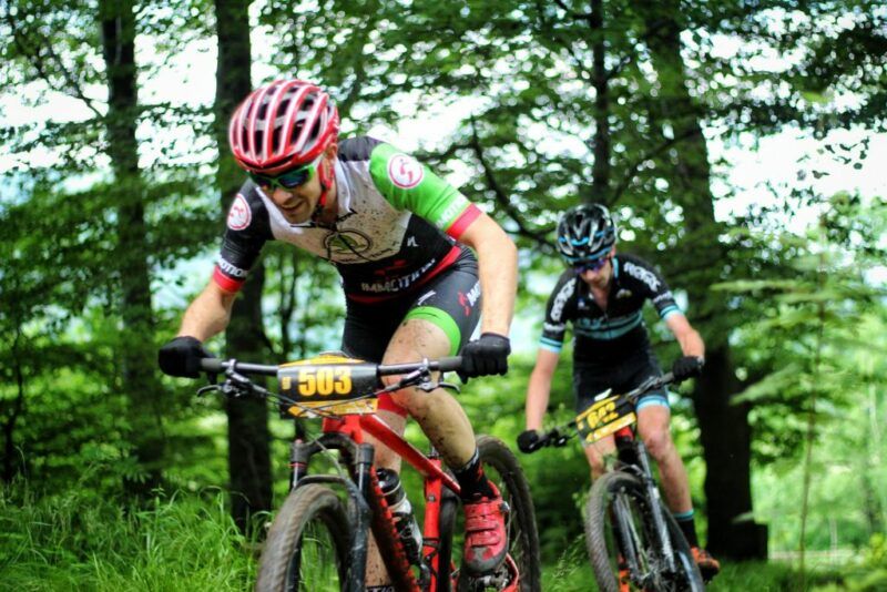 Dwóch rowerzystów jadących po ścieżce w lesie.