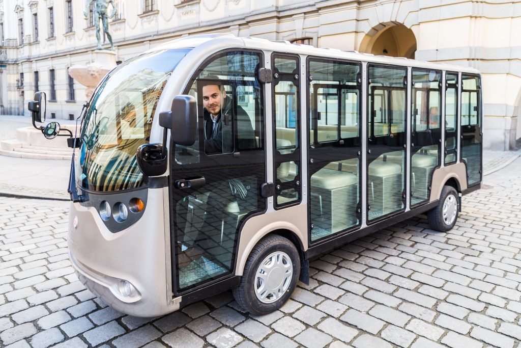 Pojazd elektryczny z kierowcą zaparkowany na starej kostce otaczanej w centrum Wrocławia