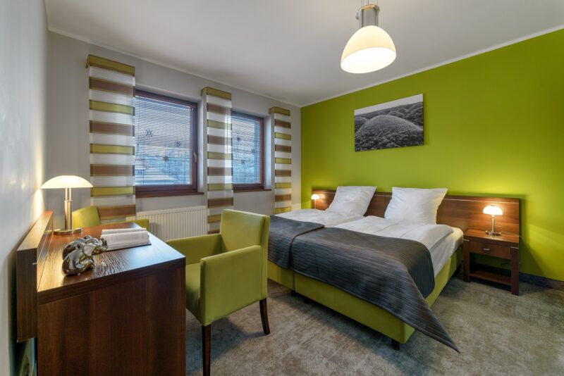 Pokój noclegowy z podwójnym łożem małżeńskim oraz biurko z fotelem.