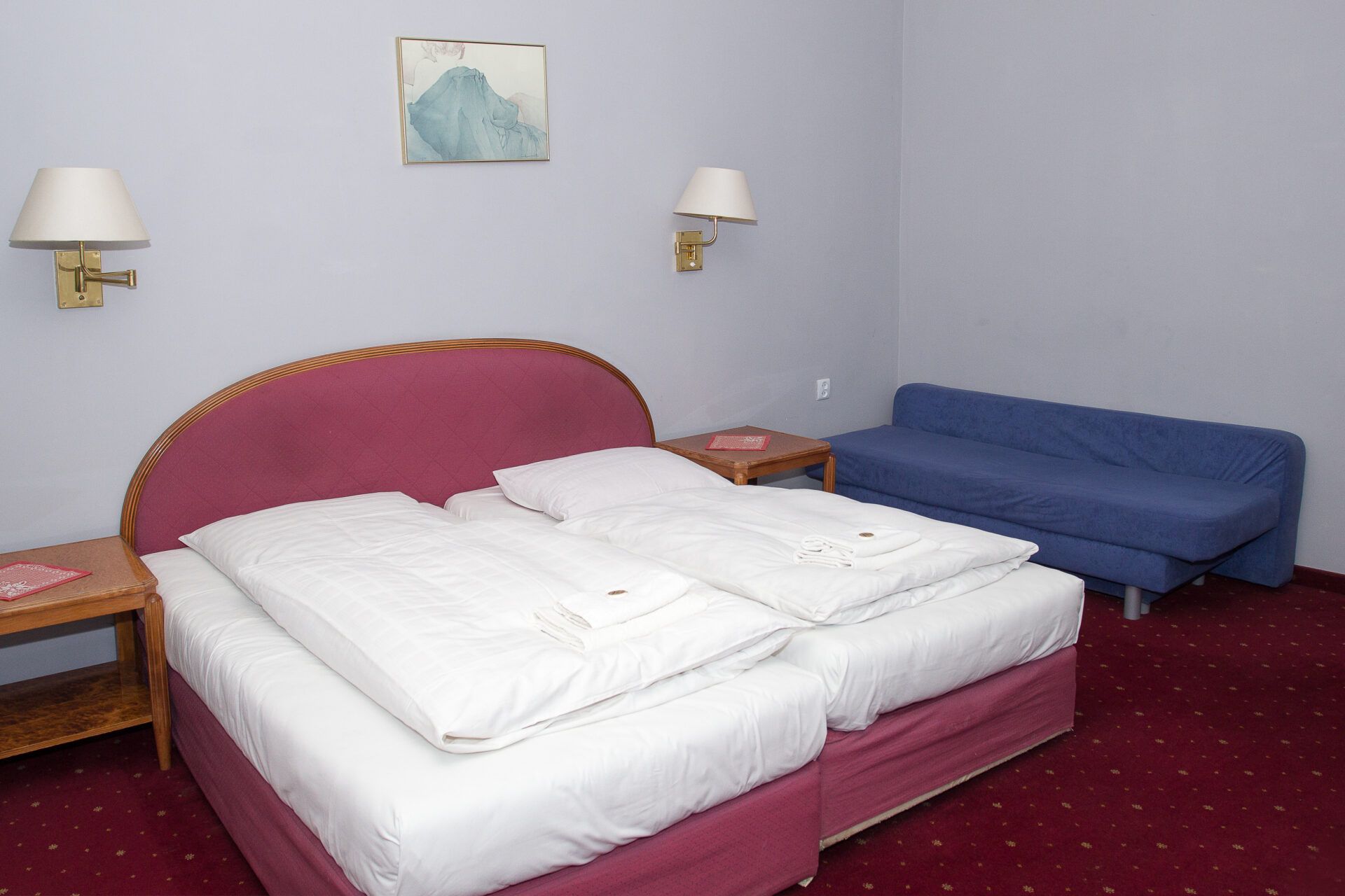 Pokój hotelowy z dużym łożem małżeńskim, z okrągłym pluszowym zagłówkiem.