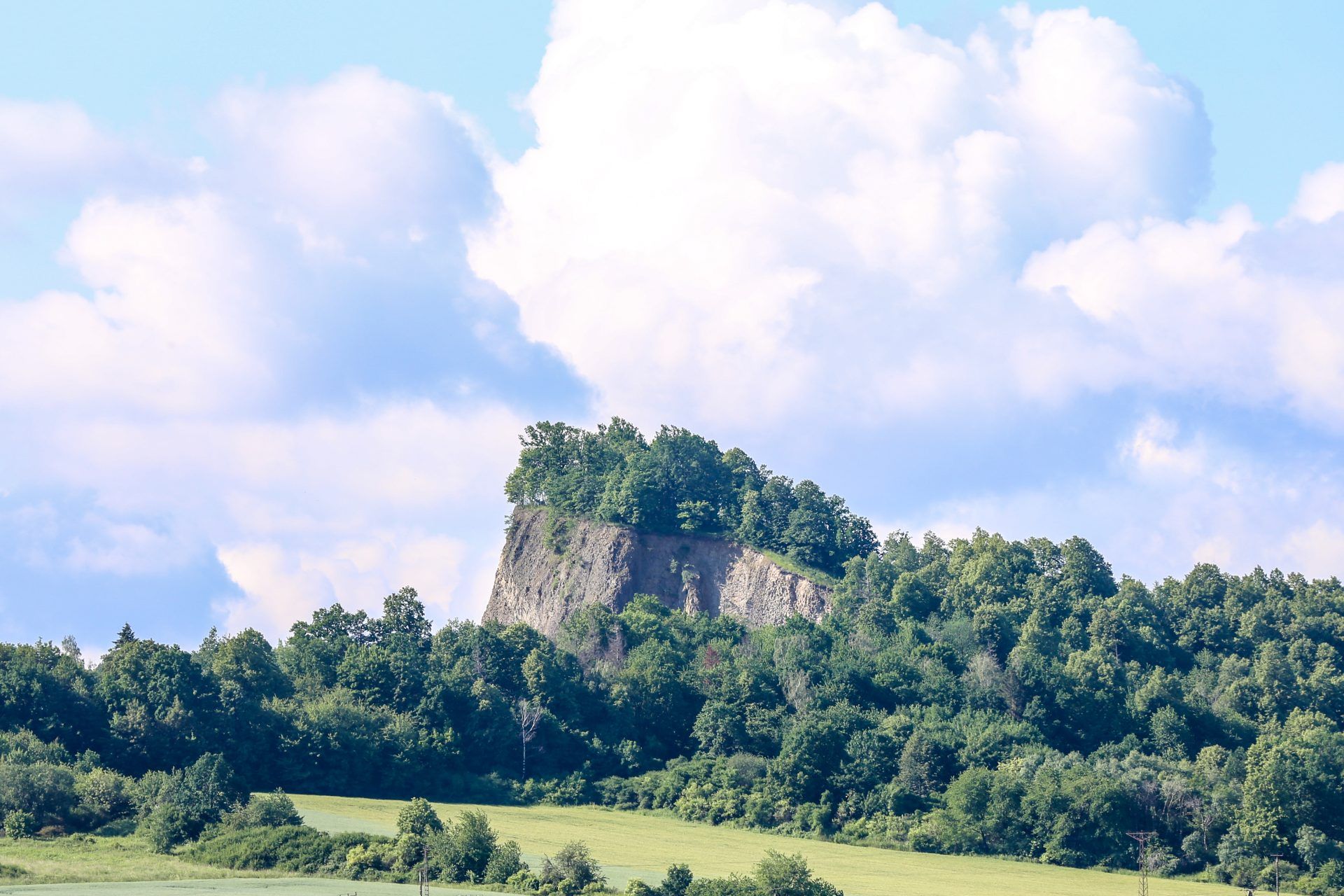 widok z daleka w słoneczny dzień na nie wysoką górę otoczoną asem