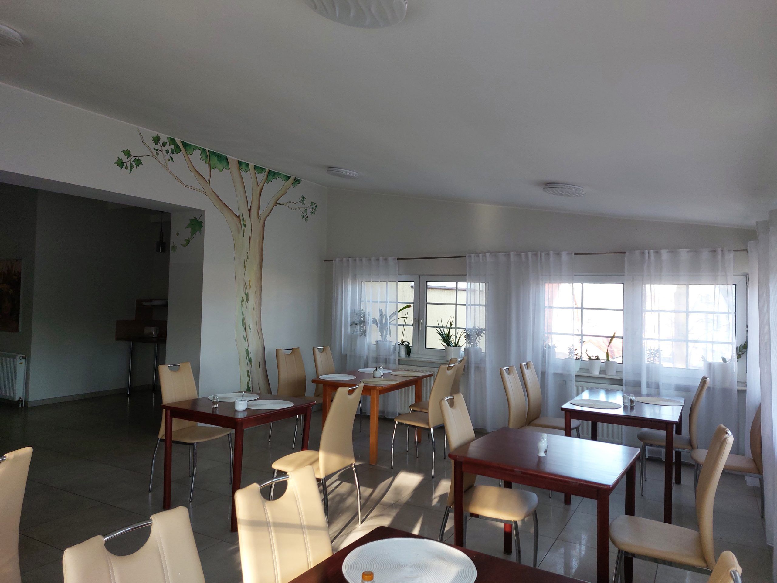 Sala restauracyjna z kilkunastoma stolikami oraz krzesłami. 