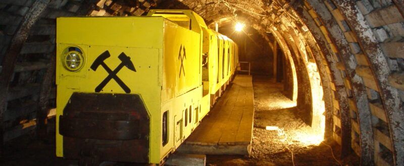 Żółte wagony kolei podziemnej stojące w oświetlonym tunelu.