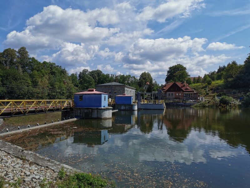 Widok z brzegu na urządzenia hydrotechniczne znajdujące się na rzece.