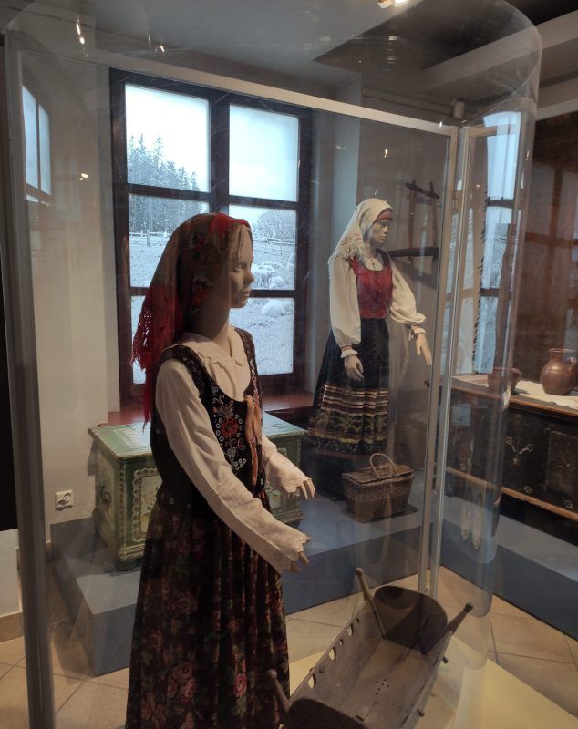 Fragment wystawy, prezentujący bogato zdobione stroje udowe.