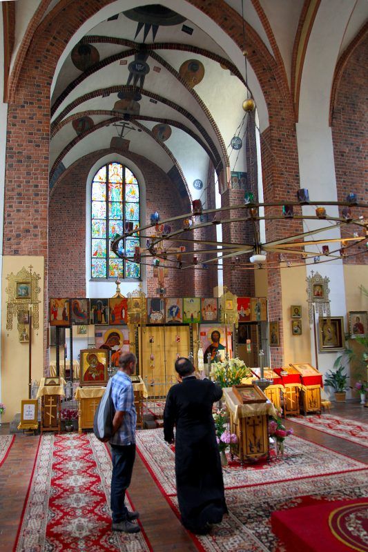 Wnętrze gotyckiej świątynie z ołtarzem i wystrojem prawosławnym.