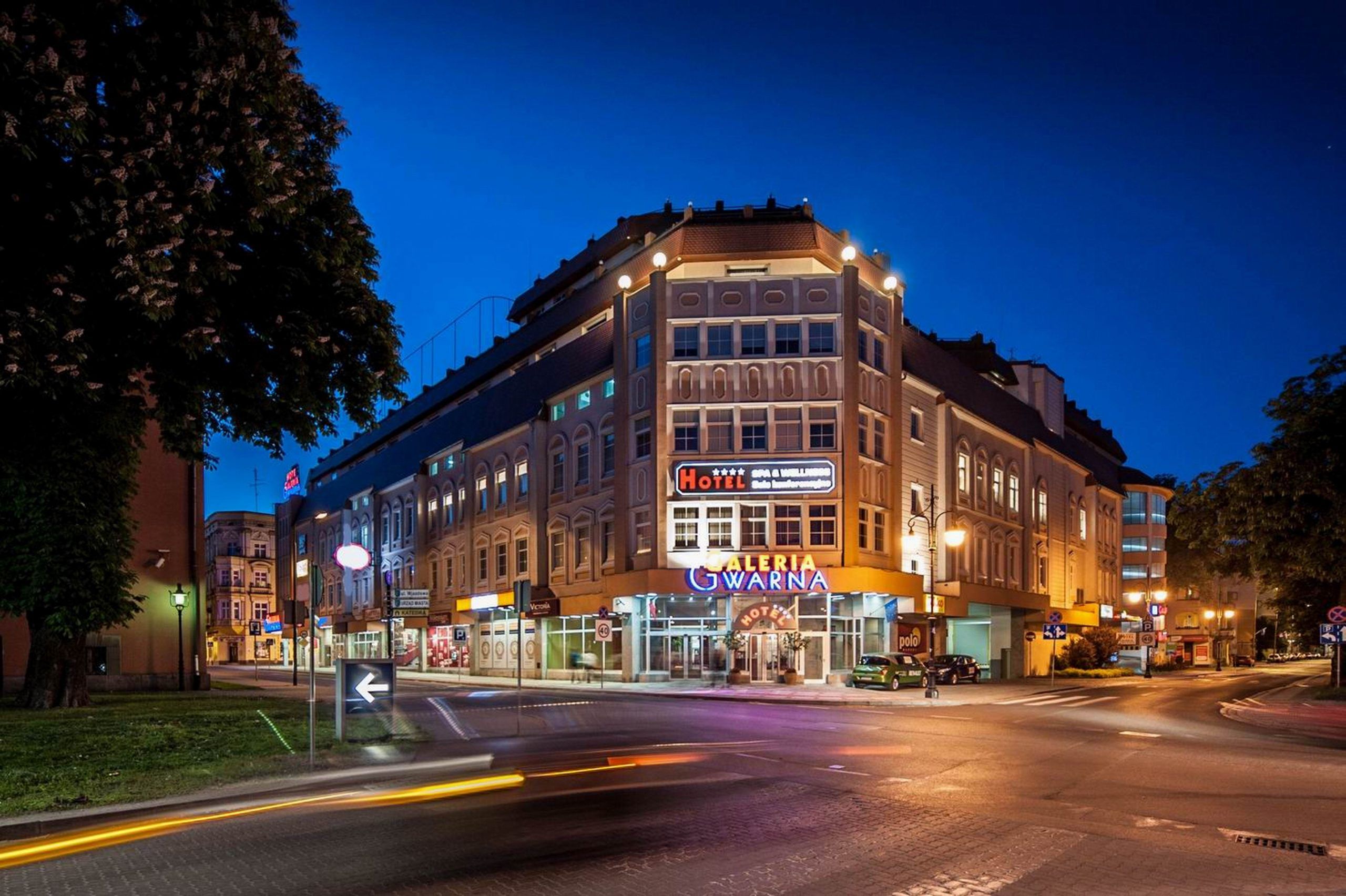 Zdjęcie dużego budynku narożnego, wykonane wieczorem. Budynek podświetlony, 
