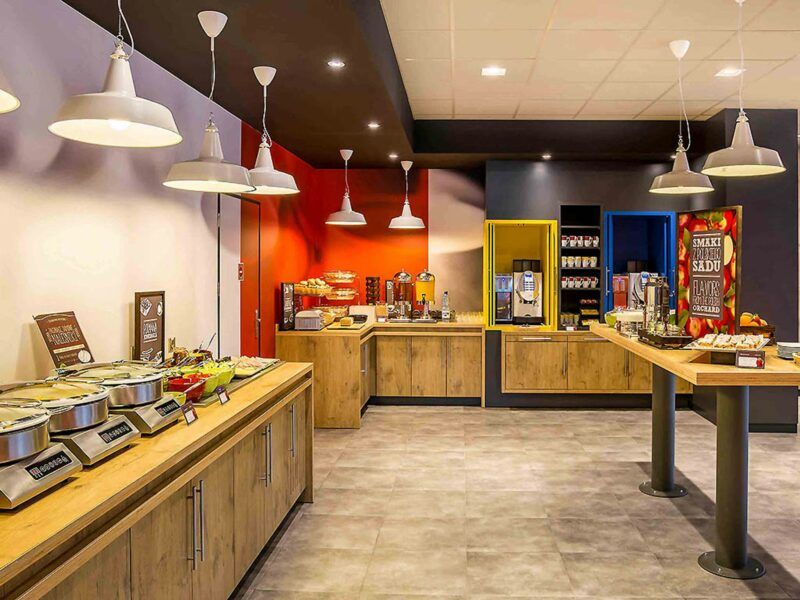 Pomieszczenie restauracyjne. Wokół ścian ustawione komody, na których znajdują się przyszykowane dania śniadaniowe.