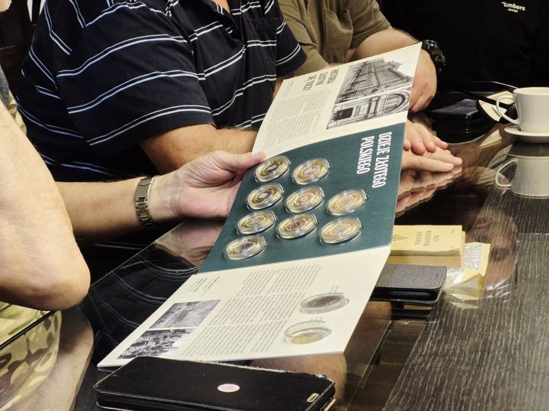 kobieta trzymająca broszurę ze starymi kolekcjonerskimi monetami