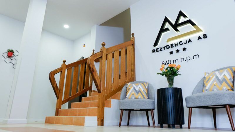 Wnętrza hotelowe z widokiem na logo hotelu oraz drewnianymi schodami.