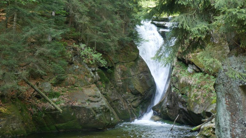 widok na wodospad, który spada pomiędzy kamieniami