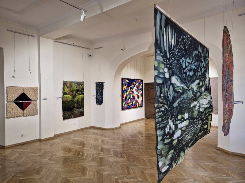 widok na sale w które wiszą na ścianach wytwory tkackie