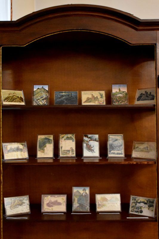 widok na drewiany regał z licznie stojącymi starymi małymi obrazami