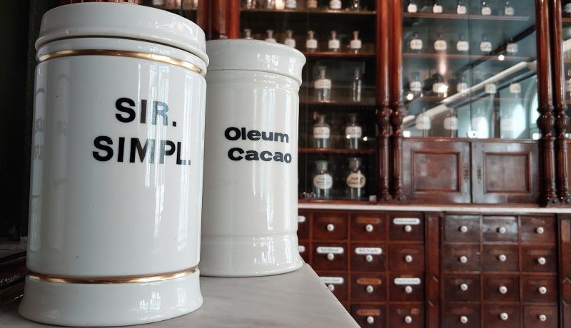 Biały dawny ceramiczny pojemnik farmaceutyczny w tle wyposażenie dawnej apteki