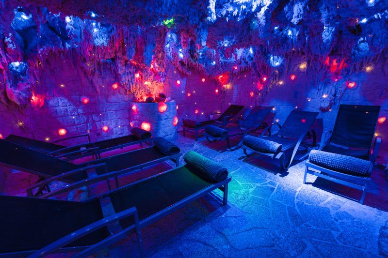 Podświetlona na niebiesko grota solna z leżakami wypoczynkowymi. 
