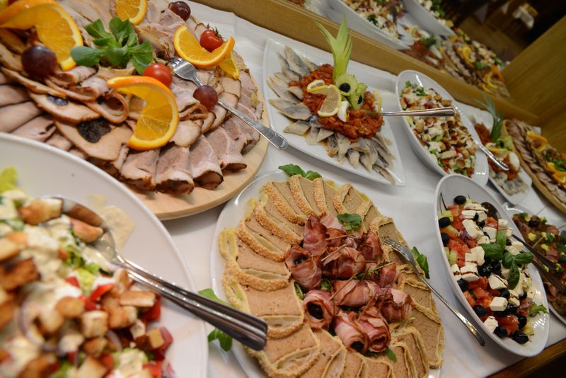 Stół zastawiony zimnymi przekąskami. Paleta wędlin, mini koreczki, warzywa