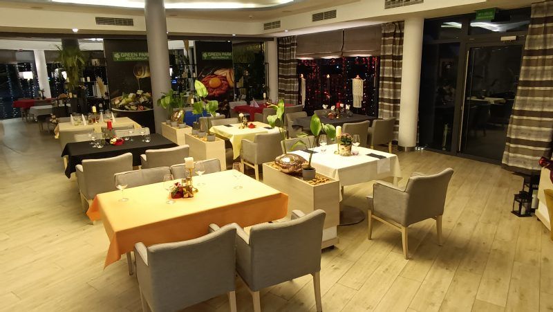 Nowoczesne wnętrze restauracji z dwoma rzędami stolików, nakrytych obrusami. 