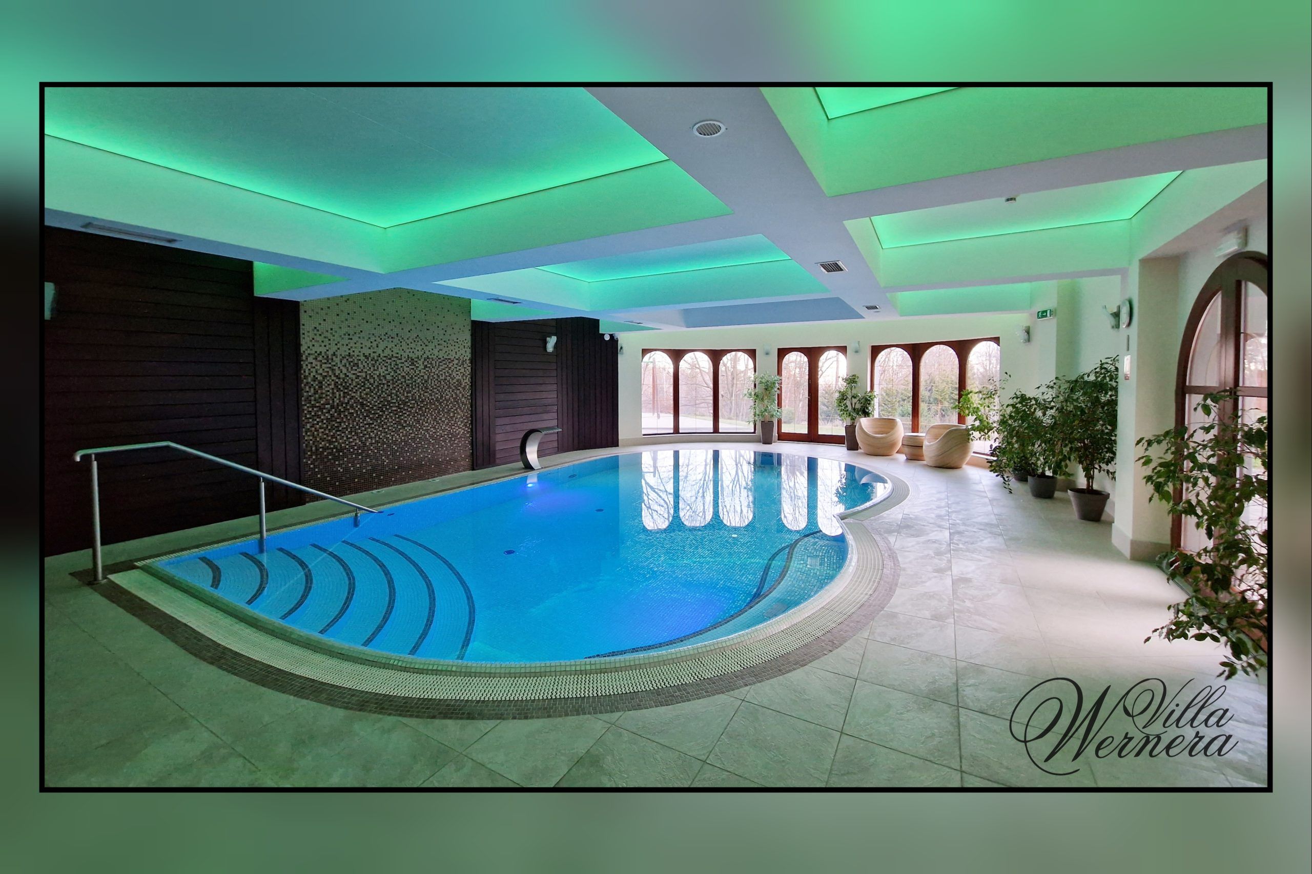 Luksusowy basen hotelowy z nowoczesnym designem, podświetlanym sufitem i elegancką strefą relaksu. Przy oknach w donicach rożliny zielone.