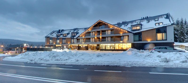 Podłużny budynek hotelowy zlokalizowany tuż przy drodze w zimowej aurze. 