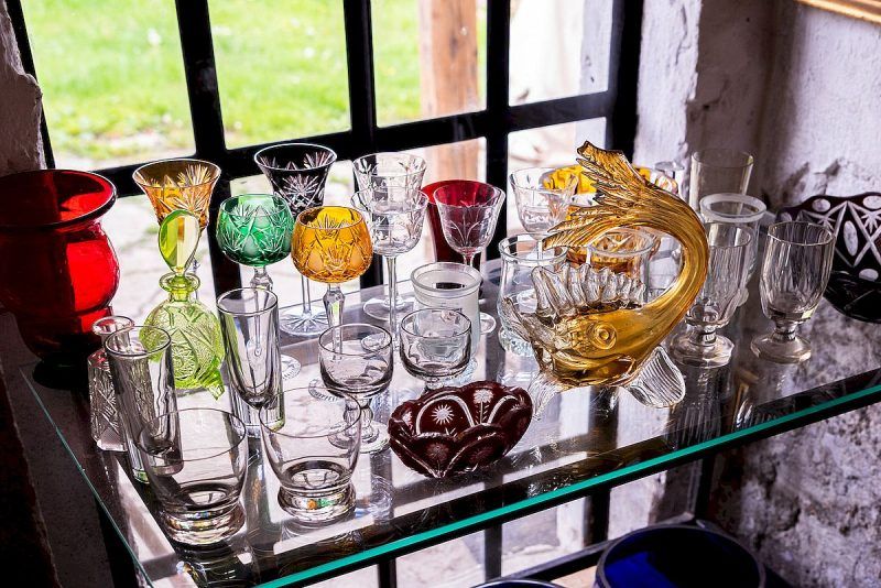 widok na półkę na której stroją różne twory ze szkła w rozmaitych kolorach