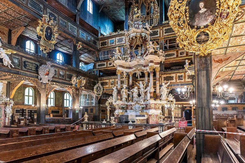 Grafika przedstawia wnętrze drewnianego kościoła