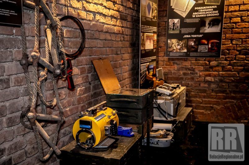 zdjęcie przedstawia narzędzia w ciemnym pomieszczeniu, leżące na drewnianych półkach