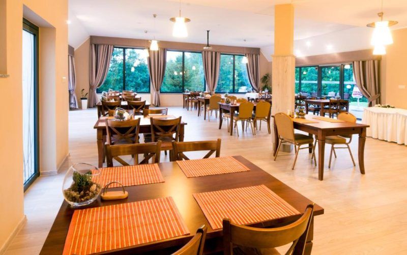 Przestronna, elegancko urządzona sala restauracyjna z dużymi oknami tarasowymi.