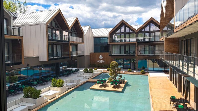 Dziedziniec wewnętrzny kompleksu hotelowego z basenem . Nowoczesny budynek podzielony został na fasady zakończone stromymi trójkątnymi dachami, a każde piętro posiada duże szklane okna oraz balkony. 