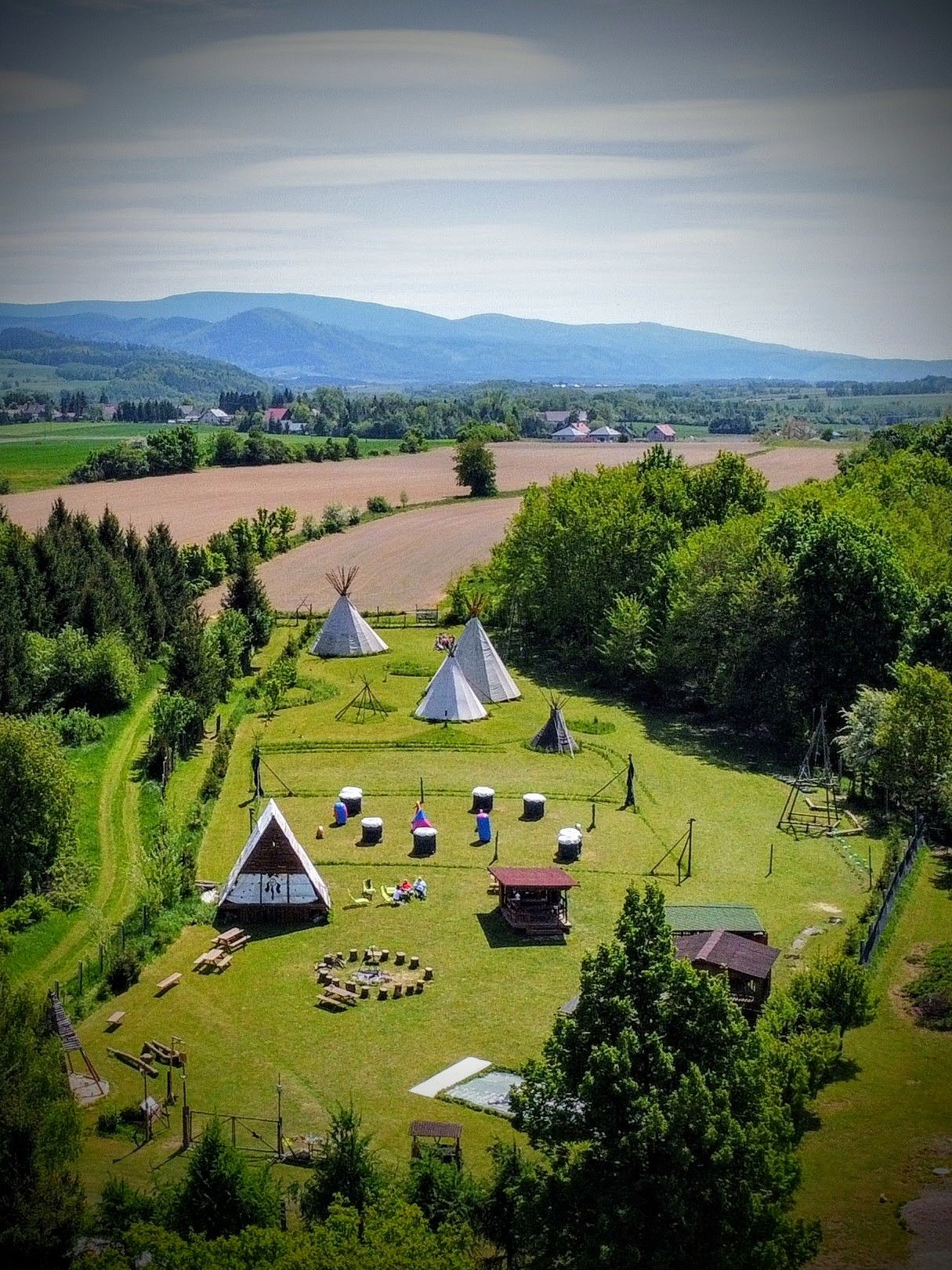 widok z drona na wioskę indiańską, w której znajdują się białe namioty i trójkątne domki