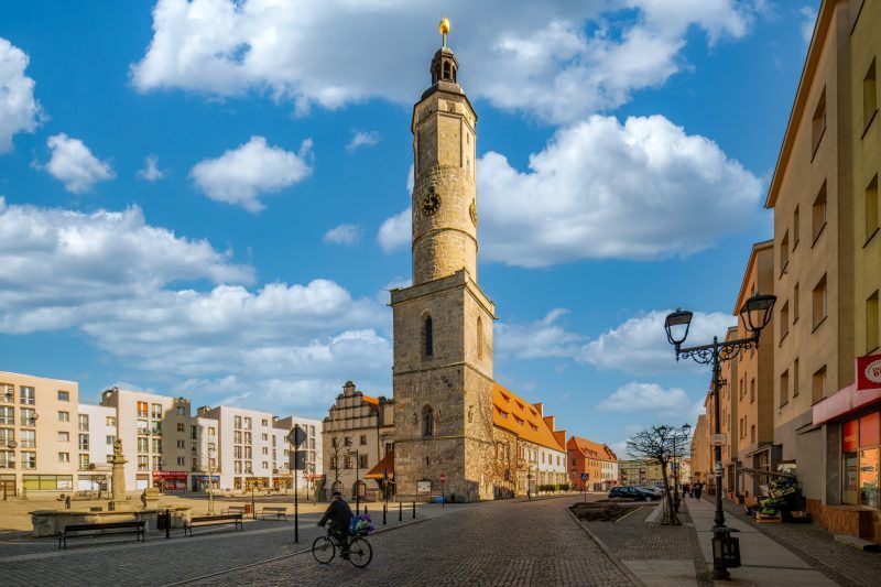 Imponujący budynek w stylu renesansowym z charakterystyczną wieżą zegarową, bogato zdobioną elewacją i strzelistymi dachami.