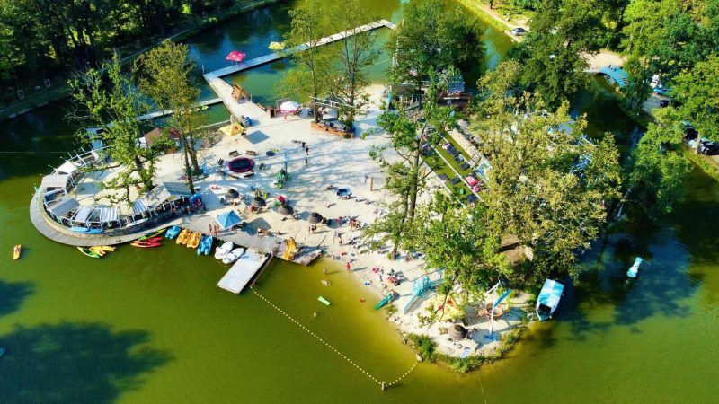 Widok z lotu ptaka na cypel z plażą i zapleczem wodnym na jeziorze w otoczeniu drzew