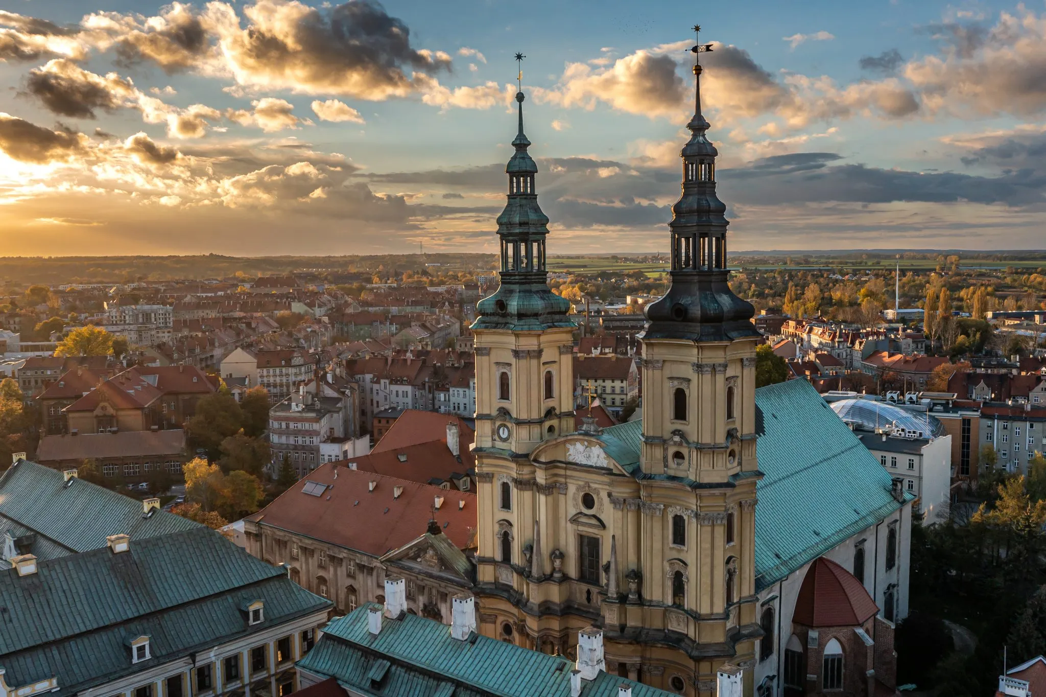 La Chiesa di San Giovanni e il Mausoleo dei Piast a Legnica, con le sue due torri barocche, sovrasta i tetti della città alla luce del sole al tramonto.